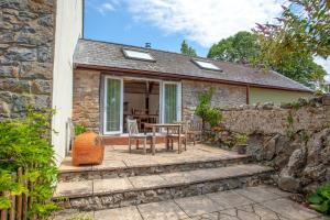 a stone cottage with a table and chairs on a patio at Hideaway Cottages - Greenacres Estates in Tenby