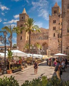 a woman walking in front of a building with palm trees at Meravigghia Suites Cefalù in Cefalù