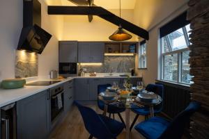 a kitchen with a table and blue chairs in it at Spacious - Contemporary 2BR Apartment - Central Ambleside - Parking in Ambleside