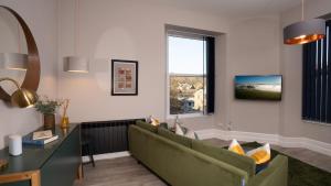 ein Wohnzimmer mit einem grünen Sofa und einem Fenster in der Unterkunft Calm - 1BR - 1BA - Apartment - Central Ambleside in Ambleside