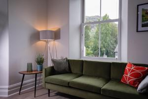 a living room with a green couch and a window at Spacious Apartment in Coniston, by LetMeStay in Coniston