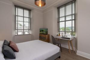 um quarto com uma cama, uma secretária e janelas em Spacious Apartment in Coniston, by LetMeStay em Coniston