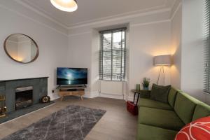 a living room with a green couch and a fireplace at Spacious Apartment in Coniston, by LetMeStay in Coniston