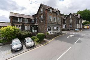 two cars parked in front of a large brick building at Spacious Apartment in Coniston, by LetMeStay in Coniston