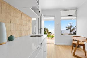 a kitchen with white counters and a table and a window at Cobble + Stone in Port Lincoln