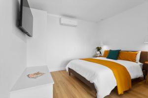 Dormitorio blanco con cama con almohadas de color naranja y verde en Cobble + Stone, en Port Lincoln
