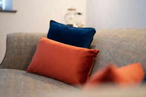 an orange and blue pillow on a couch at Spacious - Contemporary Home - Central Ambleside - Parking in Ambleside