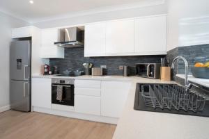 a kitchen with white cabinets and stainless steel appliances at Redbanks Apartment in Ambleside +24 photos