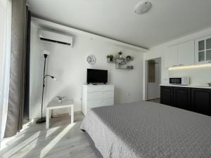 a white bedroom with a bed and a kitchen at Студио Симона 4 - първа линия море in Lozenets