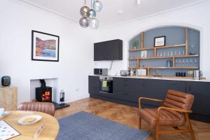 a kitchen with blue cabinets and a table and a fireplace at Loughrigg at Lipwood - Stunning 2 Bedroom - 1 Bathroom - Gentleman's Residence - Central Windermere in Windermere