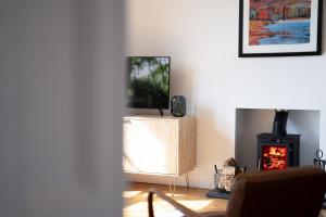 a living room with a tv and a stove at Loughrigg at Lipwood - Stunning 2 Bedroom - 1 Bathroom - Gentleman's Residence - Central Windermere in Windermere