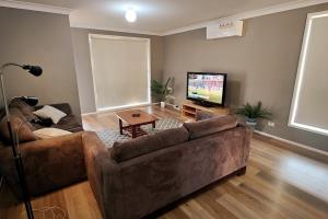 ein Wohnzimmer mit einem braunen Sofa und einem Flachbild-TV in der Unterkunft Spacious 3 bedrooms Duplex Free parking in Liverpool