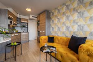 a living room with a yellow couch and a kitchen at Starter 24 Wrocław in Wrocław