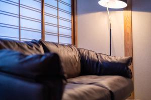 un sofá de cuero marrón en una sala de estar con lámpara en Tsukasa Ryokan en Saga