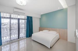 1 dormitorio con cama blanca y ventana grande en 春雨漫居 Spring Rain Hostel, en Meishan