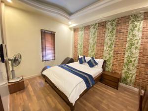 a bedroom with a bed and a brick wall at Rose Hotel in Hai Phong