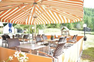 a patio with tables and chairs under a large umbrella at Restaurant & Hostel Hole in One in Randa