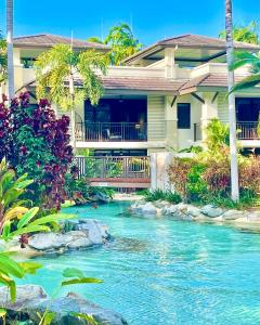 a house with a river in front of it at Tropical Retreat - Poolside Swimout - Ground Floor - Sea Temple Resort & Spa Port Douglas in Port Douglas