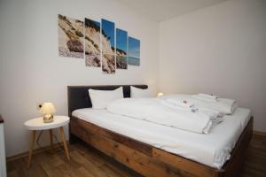 a bedroom with a bed with white sheets and a table at Ferienhus Baabe bei Familie Vergien in Baabe