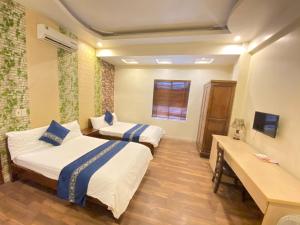 a hotel room with two beds and a desk at Rose Hotel in Hai Phong