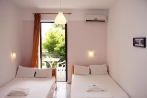 two beds in a room with a balcony at Hotel Geromichalos in Paralía Skotínis