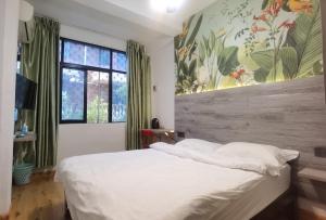 a bedroom with a white bed and a large window at Haikou Banana Hostel in Haikou