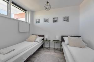a white room with two beds and a window at Grand Apartments - Fala apartament na Przymorzu in Gdańsk
