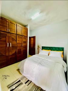 a bedroom with a large white bed with wooden cabinets at RESIDENCE LUXALYS in Yaoundé