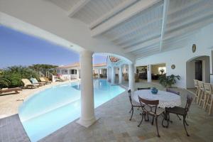 a swimming pool with a table and chairs next to a house at Spacious villa with sea view in Saint Martin + private pool. in Les Terres Basses