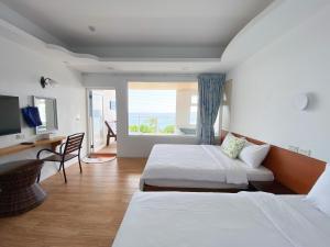 una camera da letto con due letti, una scrivania e una finestra di 南鴻雅築South Home a Nanwan
