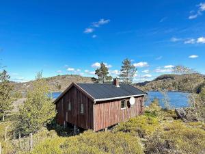 a small house sitting on the side of a lake at Two-Bedroom Holiday home in Farsund 1 in Helle