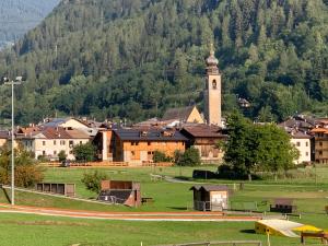 una ciudad con una torre de reloj frente a una montaña en Camelot Luxury Houses Horses en Pellizzano