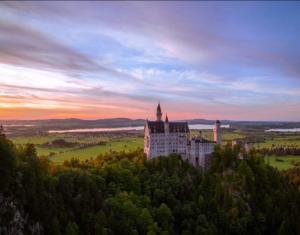 a castle on top of a hill with a sunset at Ferienwohnung Ertner in Füssen