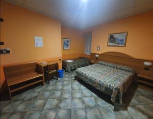 een hotelkamer met 2 bedden en een bureau bij Hotel Azalea in Baveno