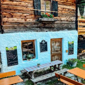 金茲林的住宿－Grawandhütte，蓝色的建筑,外面设有桌子和长凳