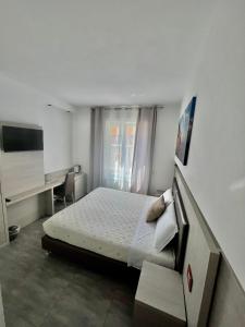 a white bedroom with a bed and a desk at Eden Rooms in La Spezia