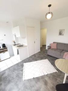 a living room with a couch and a kitchen at Le Calme - Appartement 2 pièces in Alfortville