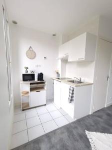 a white kitchen with a sink and a microwave at Le Calme - Appartement 2 pièces in Alfortville