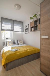 a bedroom with a large bed with a yellow blanket at StarterApart Wrocław in Wrocław