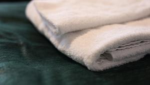 uma pilha de toalhas brancas sentadas numa cama verde em RS Lägenhetshotell Skövde em Skövde