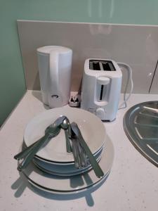 a pile of plates and utensils sitting on a counter at Letzi Private En-Suite, Near Heathrow Airport T3 in Hayes