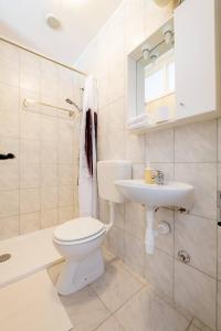 a white bathroom with a toilet and a sink at Guest House Vuljan in Hvar