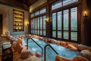 a large hot tub in a room with rocks at Legacy Yen Tu - MGallery in Uông Bí