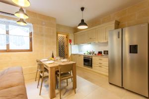 Una cocina con una mesa y un refrigerador de acero inoxidable. en Naduri, Beautiful Gozitan Villa plus Pool - Happy Rentals, en Nadur