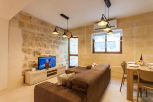a living room with a couch and a tv at Naduri, Beautiful Gozitan Villa plus Pool - Happy Rentals in Nadur