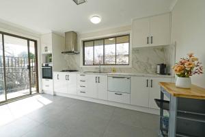 林伍德的住宿－Maroondah 3BR Brick Entire Home Free Wi-Fi Parking，一间厨房,配有白色的橱柜和大窗户