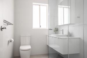 Un baño blanco con inodoro y lavabo. en Urban Rest Neutral Bay Apartments, en Sídney 11 fotos más