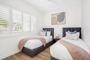 two beds in a bedroom with white walls and windows at Urban Rest Neutral Bay Apartments in Sydney