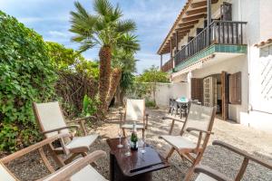 a patio with chairs and a table and a palm tree at Paola: Preciosa casa pareada con piscina in Sitges