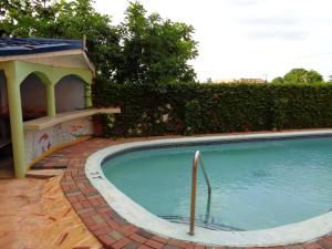 a small swimming pool with a gazebo next to a fence at Tropical Court Hotel in Montego Bay